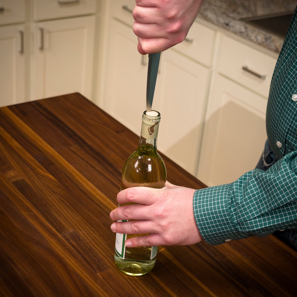 Using a knife to extract a cork from a wine bottle