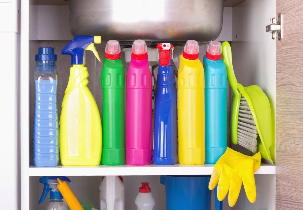 Cleaning products placed in kitchen cabinet under sink. Housekeeping storage space