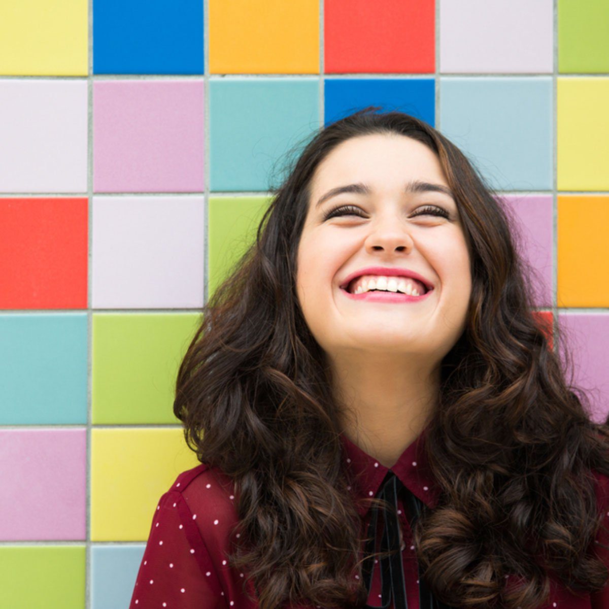 Happy girl laughing against a colorful tiles background. Concept of joy; Shutterstock ID 332500766