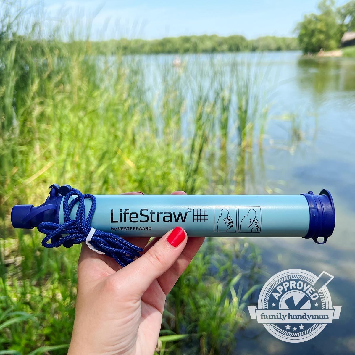 Lifestraw being held up in front of a pond in the background