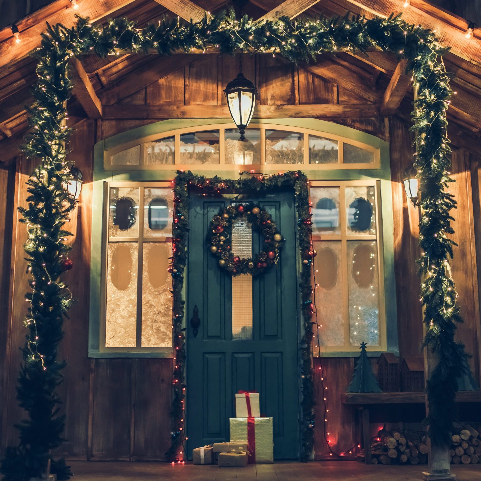 Decorated house facade with presents from Santa Claus before Christmas. Gift boxes are lying on the porch in New Year Eve.