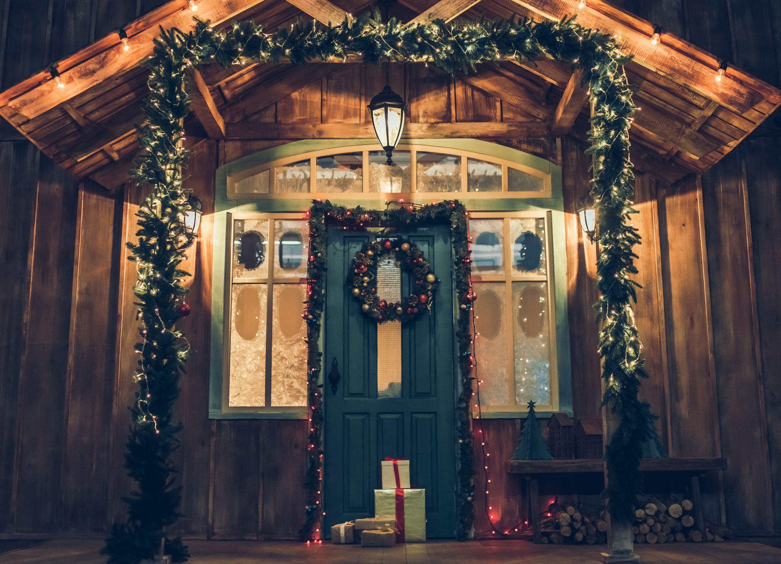 Decorated house facade with presents from Santa Claus before Christmas. Gift boxes are lying on the porch in New Year Eve.