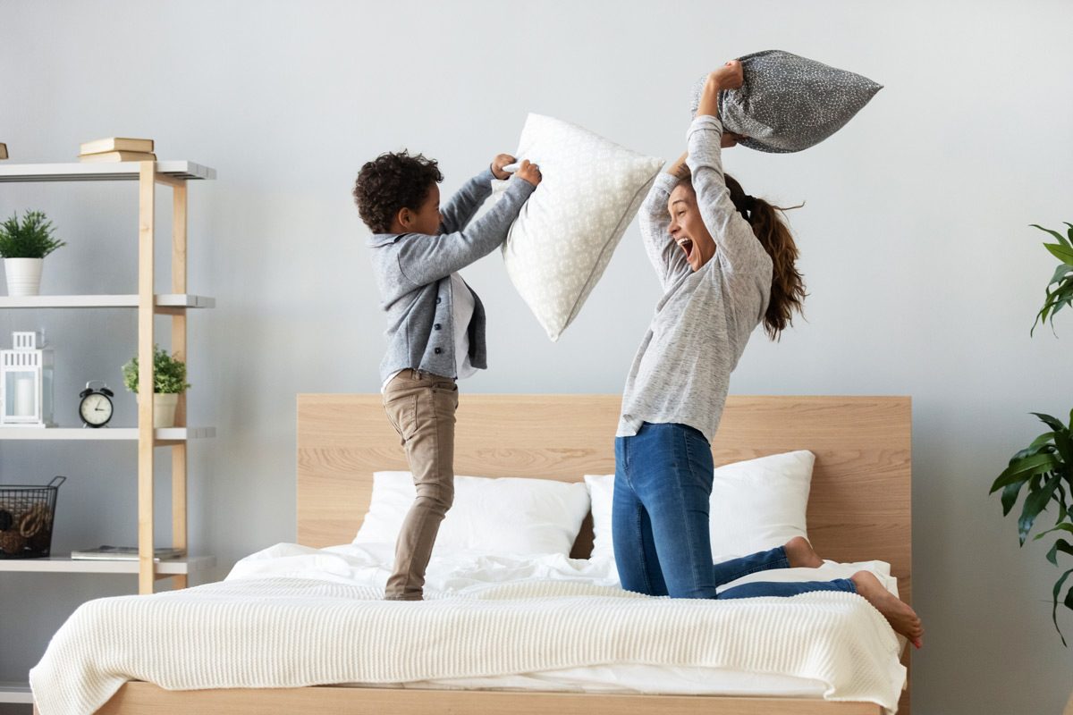 mom and son pillow fight on bed