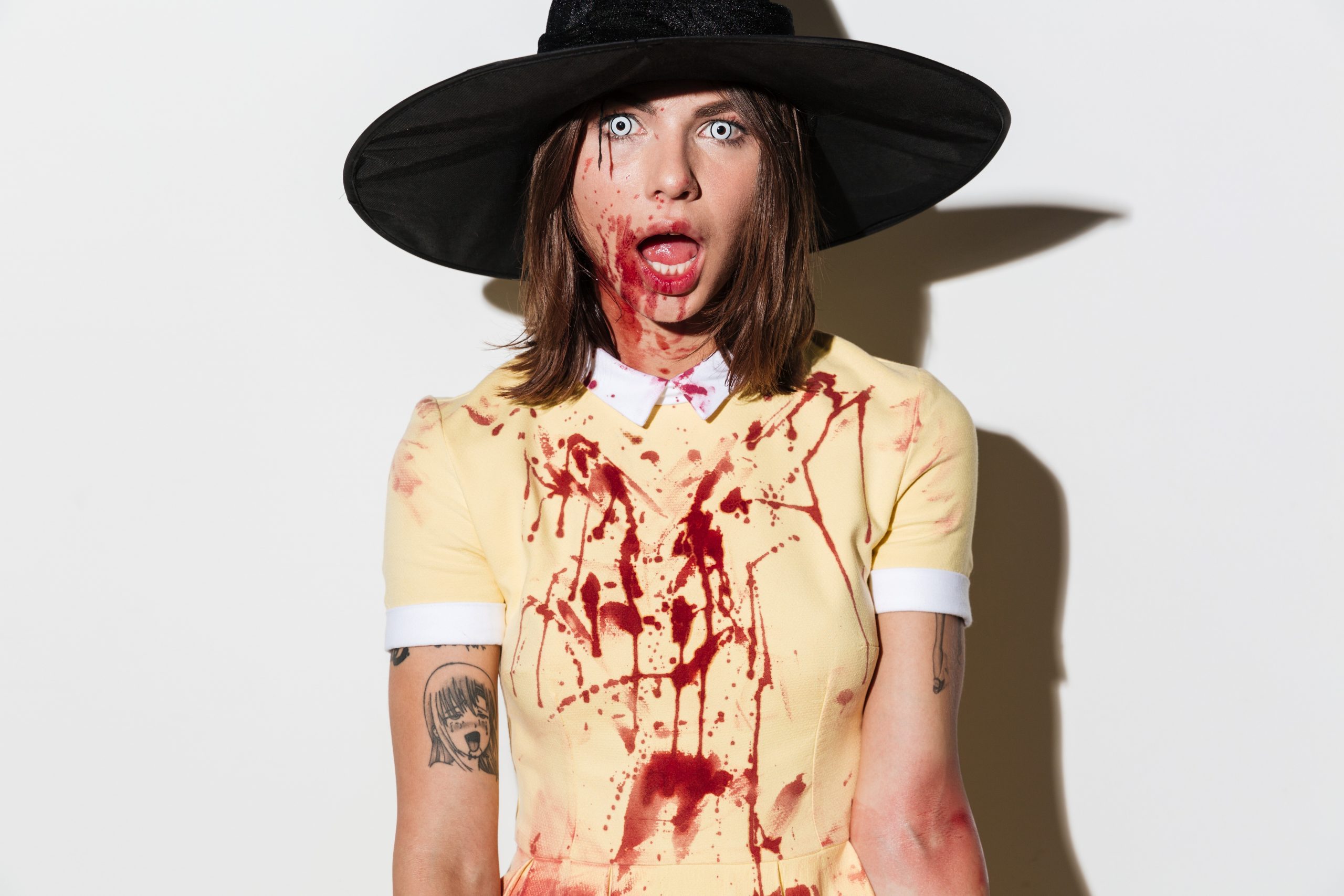 Close up image of frightening woman in halloween costume looking at the camera with open mouth over white background