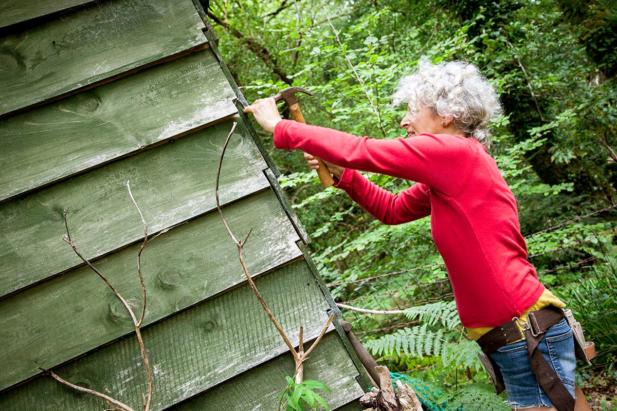 Older Woman Making Repairs To Her Cabin