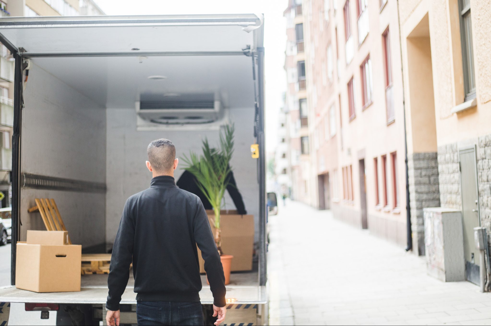 Rear view of man mover standing against truck on street in city