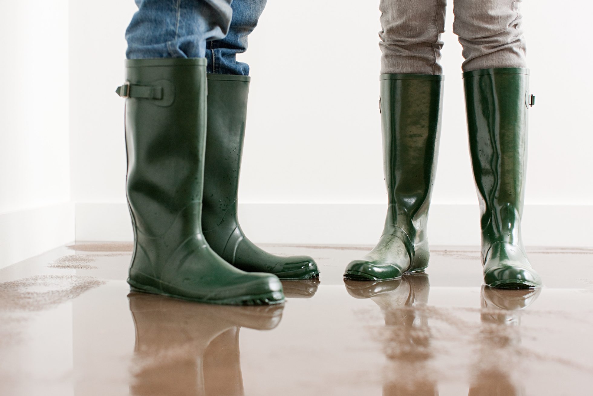 Young couple in rubber boots on flooded floor in home