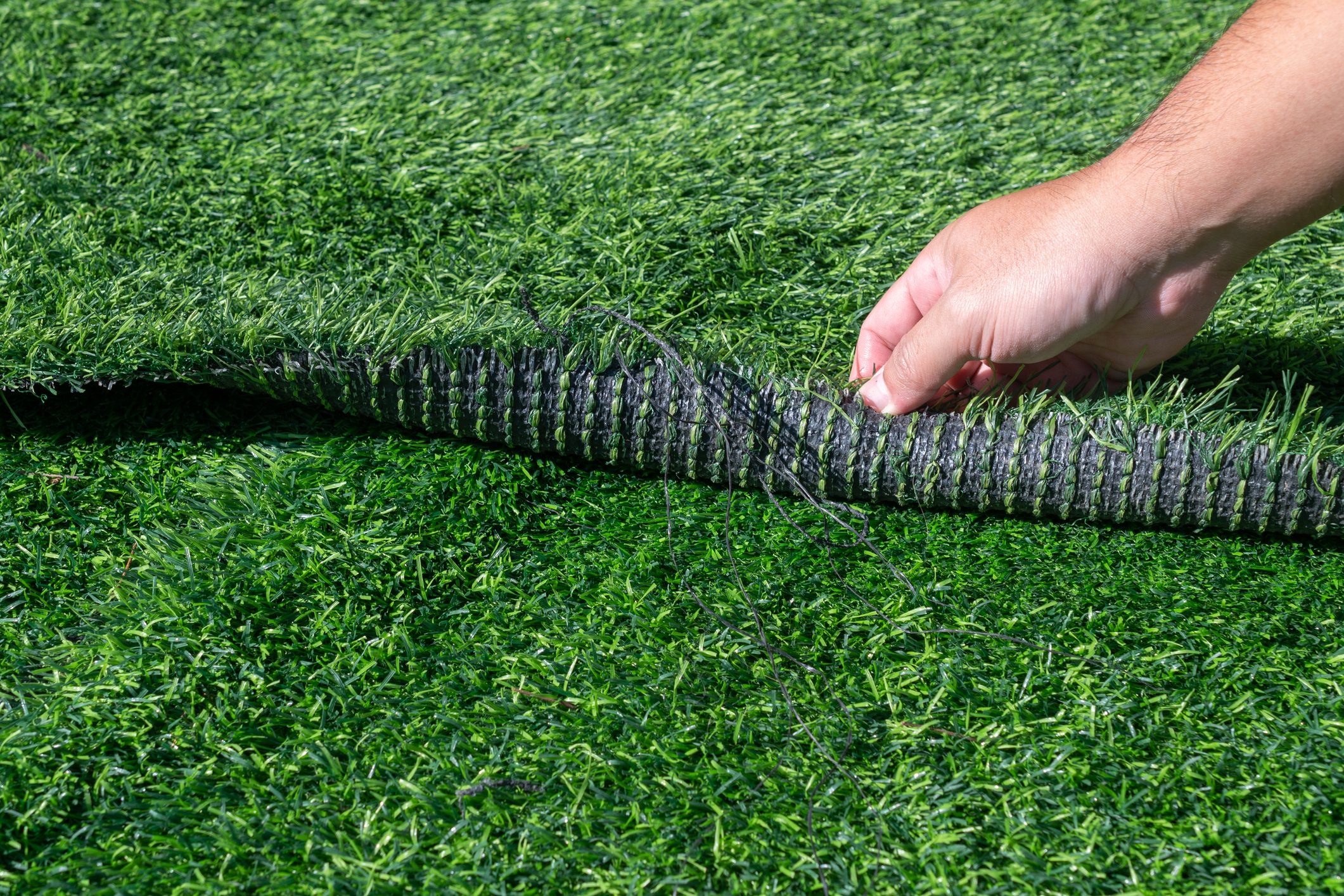 Someone hand pulling an artificial turf before replacement. Artificial turf is used for covering sport arena or garden.