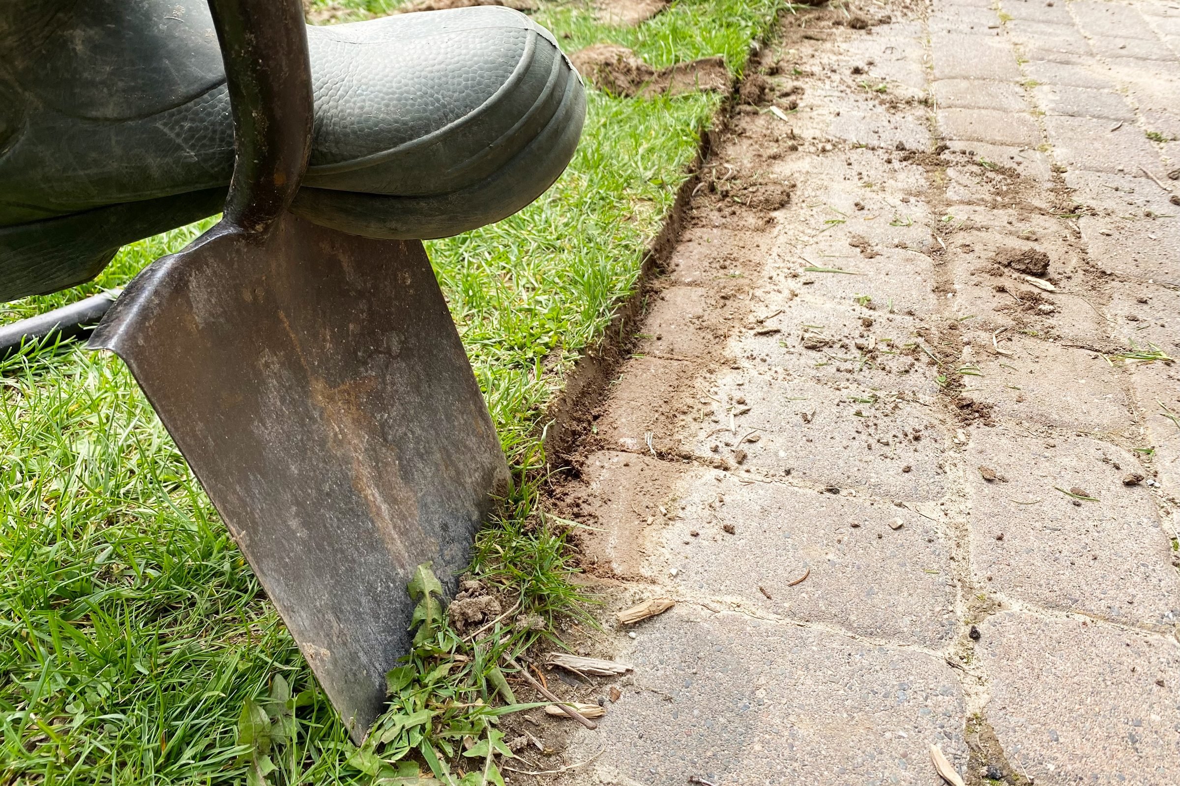 creating sharp edges in the grass next to the pavers with a shovel