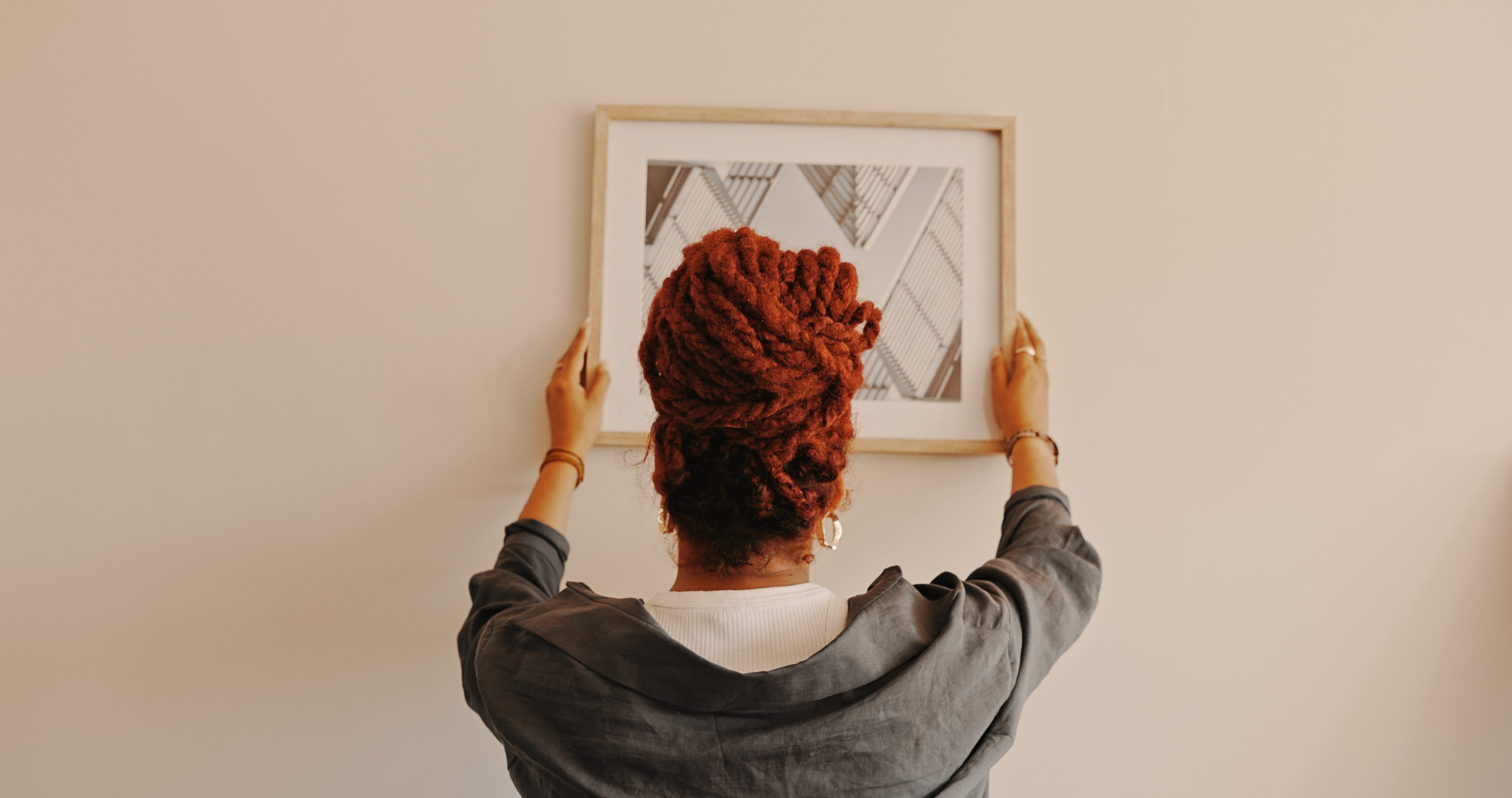 Shot of a unrecognizable female hanging a painting at home