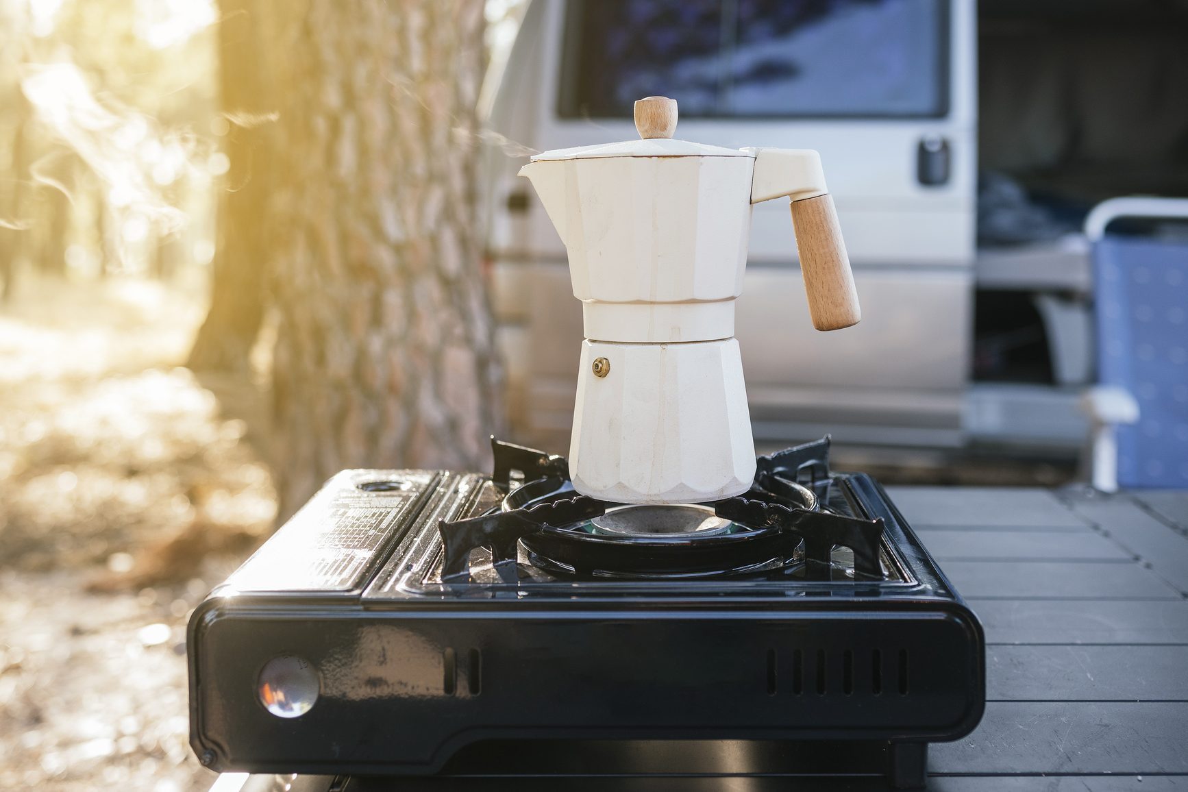 White coffee pot boiling coffee in the forest.