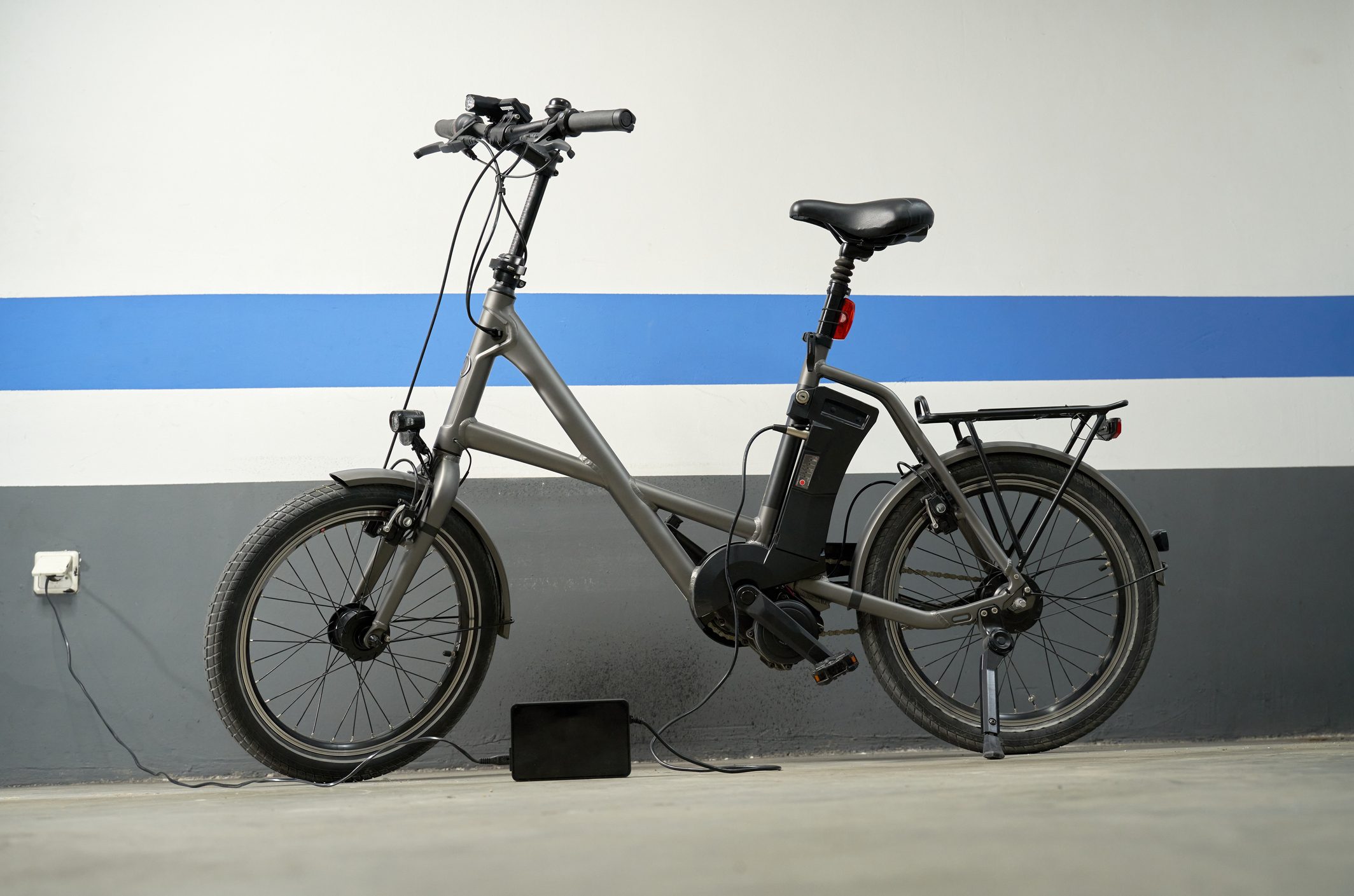 Electric bicycle charging the electrical battery at garage. Environmental concept.