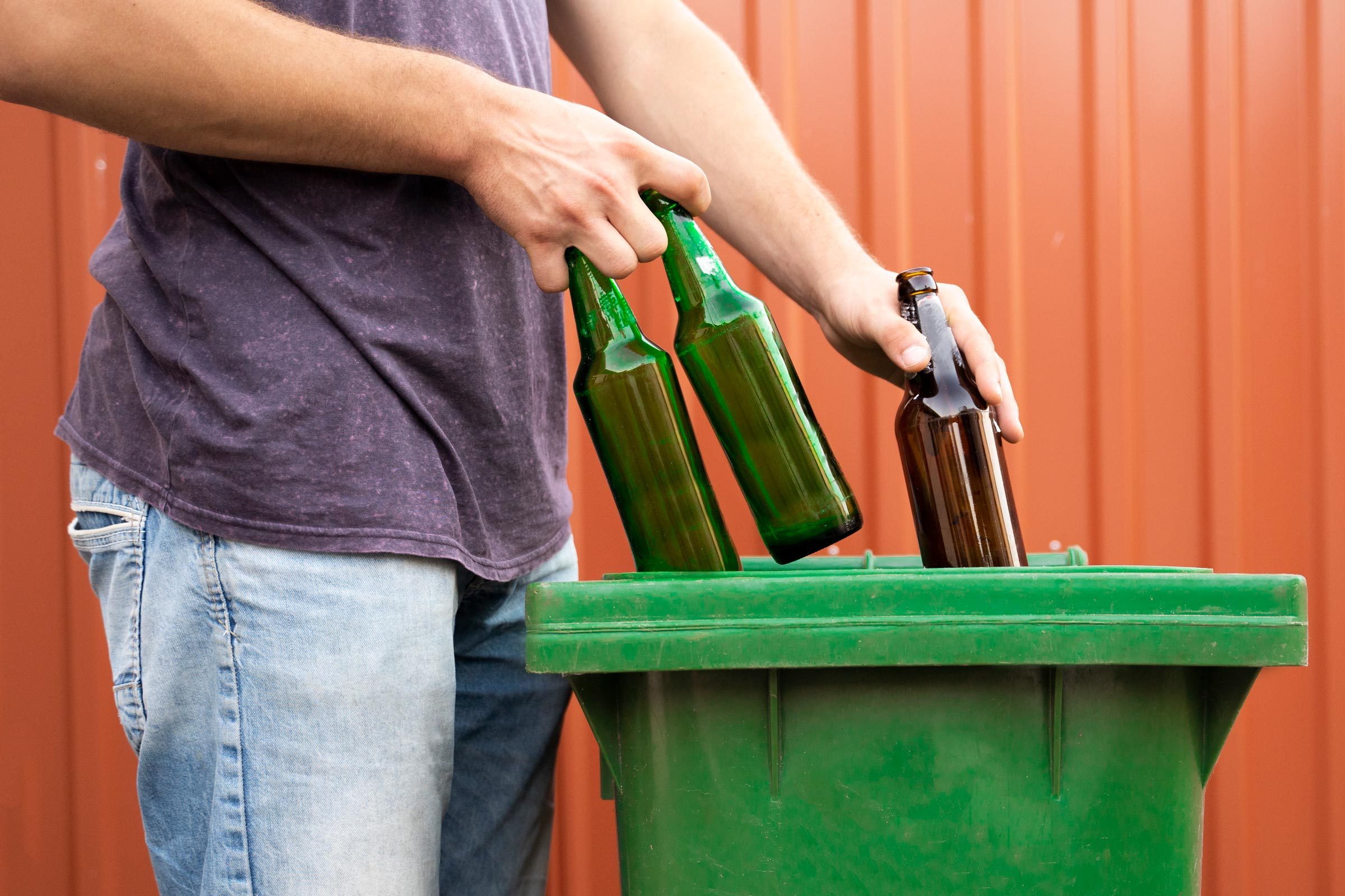 Man putting glass bottles in recycle bin