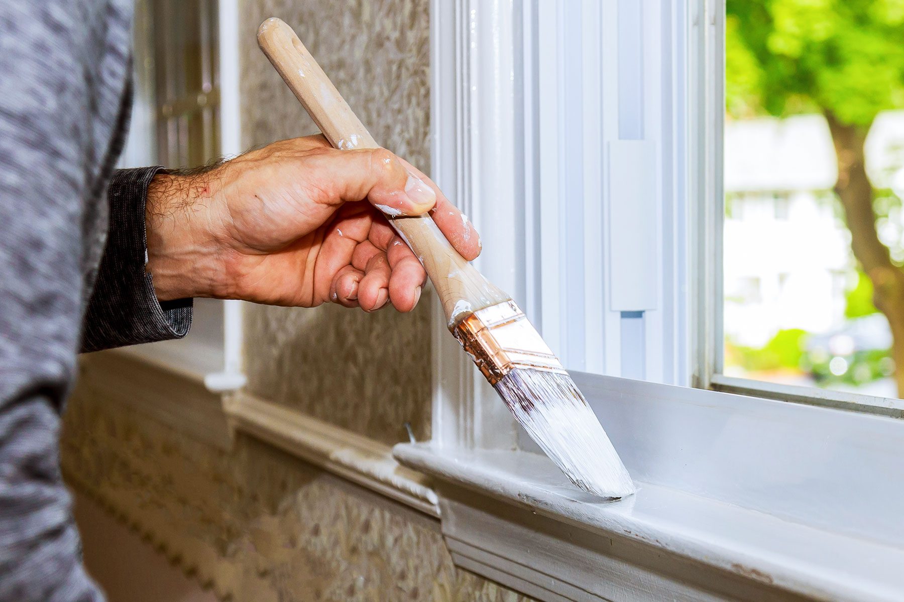 Hand with paintbrush painting a window white