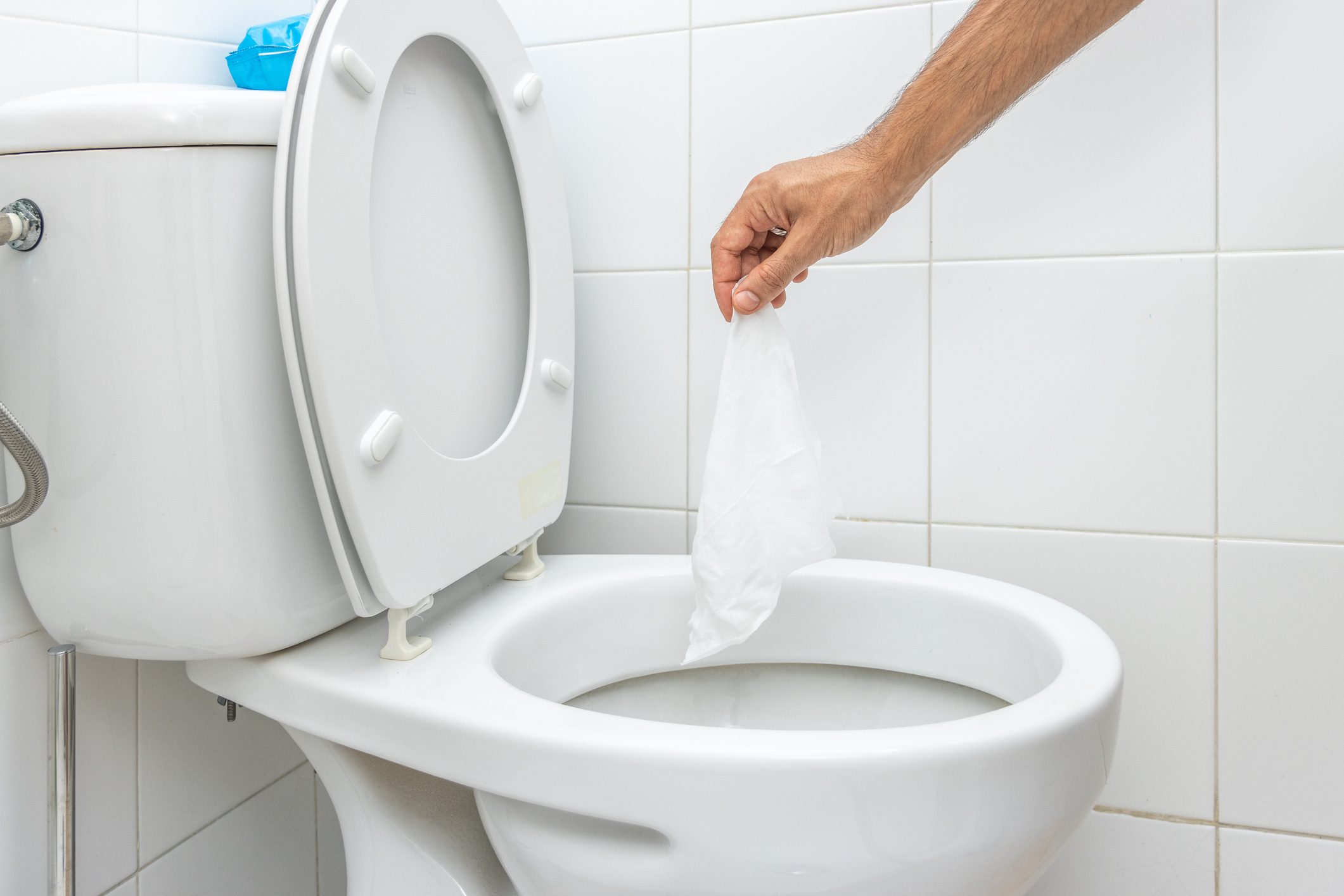 Hand throwing wet wipe into toilet