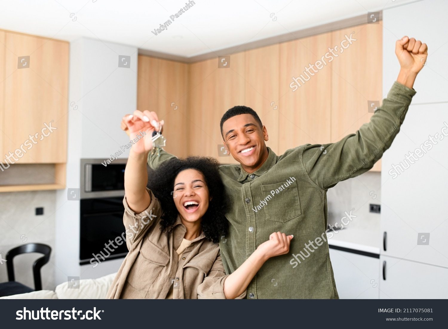 Stock Photo Multiracial Couple In Love Hugging In A New Home While Holding Keys In Hands Young Multiracial 2117075081