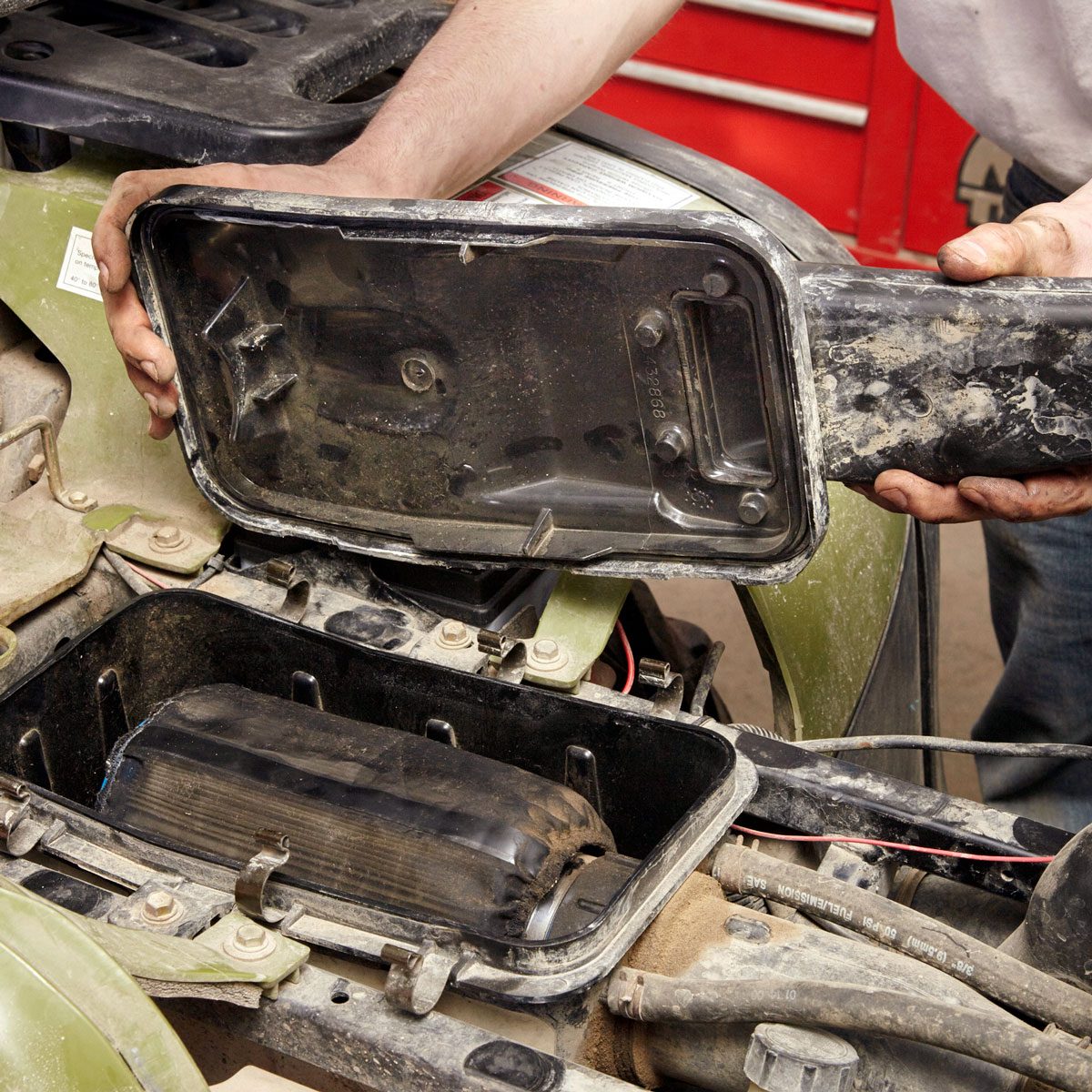 Hands can be seen opening the air cleaner cover