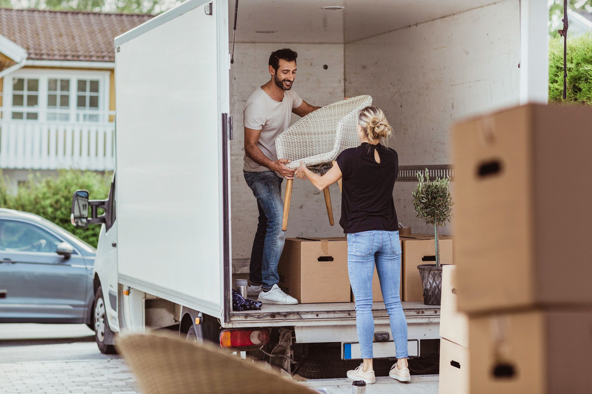 Smiling Male And Female Partners Unloading Chair From Van