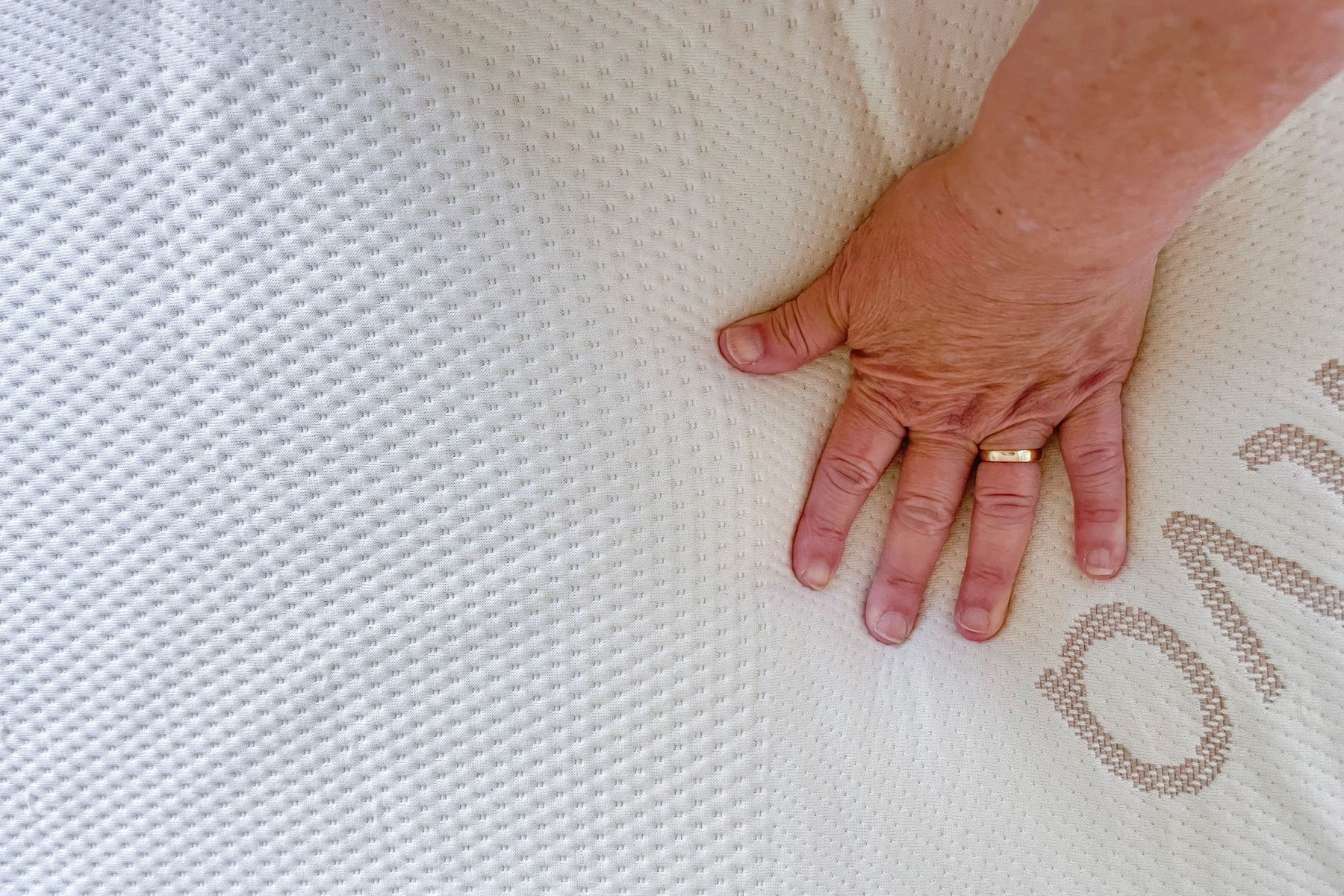 Hand pressing into mattress topper.