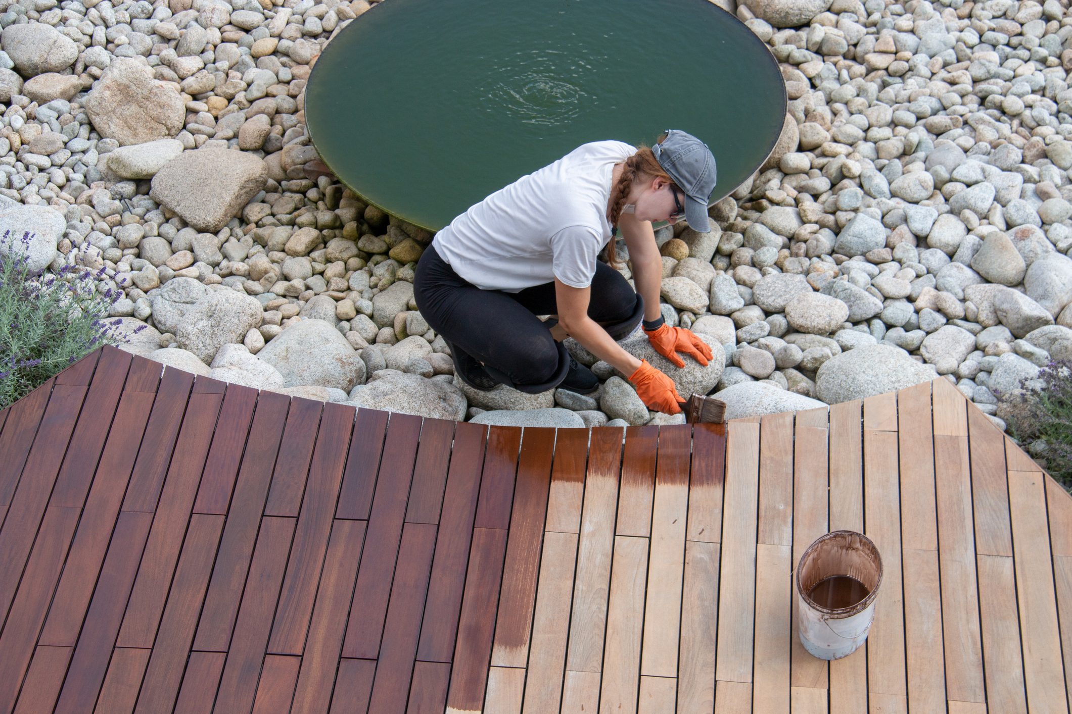 Female worker applying deck protection sealer